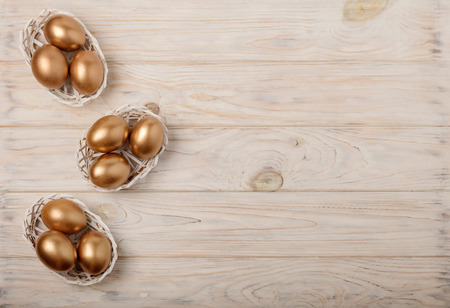 Happy easter! Easter decor and Easter eggs of golden color on a light wooden background. Selective focus.の写真素材