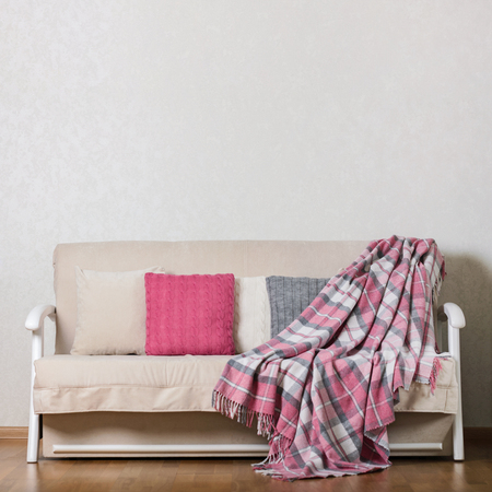 Beige sofa with plaid and colorful pillows (pink, grey, white) in the living room. Selective focus.の写真素材