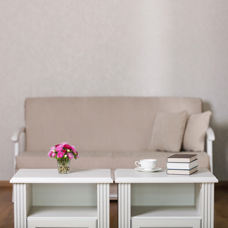 Beige sofa with pillows in the living room and vase with Flowers (Michaelmas daisy, asters). Selective focus.の写真素材