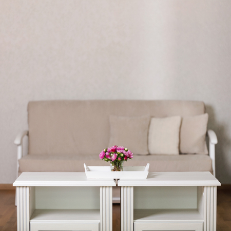 Beige sofa with pillows in the living room and vase with Flowers (Michaelmas daisy, asters). Selective focus.の写真素材