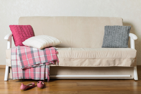 Beige sofa with plaid and colorful pillows (pink, grey, white) in the living room. Selective focus.の写真素材