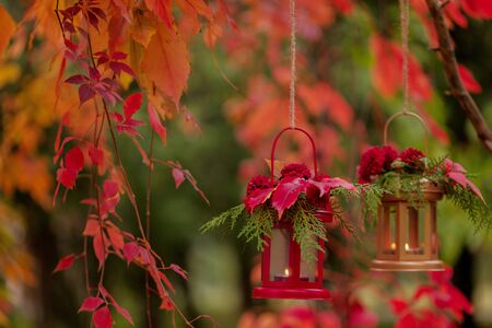 Fall time. Autumn decoration. Candlesticks in the form of lanterns with daisy decor, juniper and autumn red leaves. Selective focus.の写真素材