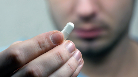 closeup man face taking white pill,