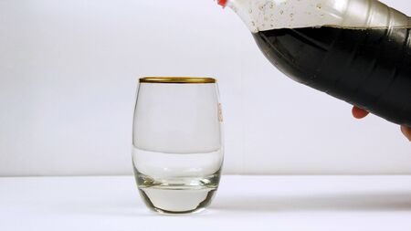 Pouring soda from the bottle into a glassの写真素材