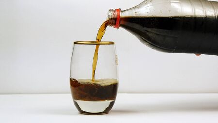 Pouring soda from the bottle into a glassの写真素材