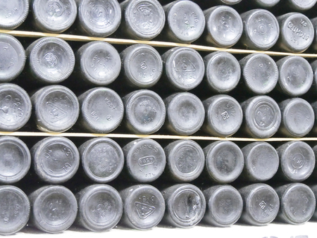 Old bottles of wine in rows in wine cellar. Rows of many wine bottles in winery cellar storage....
