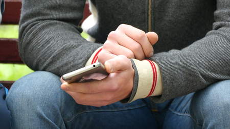 Man with a smartphone in his hands shows something to another person and gesturing.