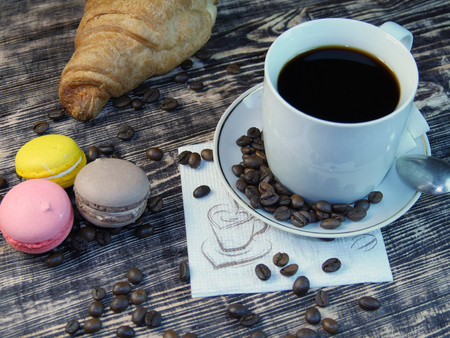 Coffee and macarones rotating on wooden table.の写真素材