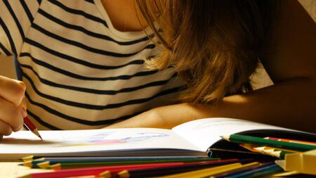 Attractive girl in glasses draws coloring book. Close up