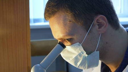 laboratory  doctor looking through a microscope.