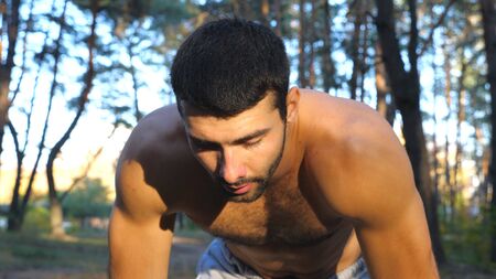 Portrait of tired guy taking break after hard run workout in forest. Sportsman resting after...
