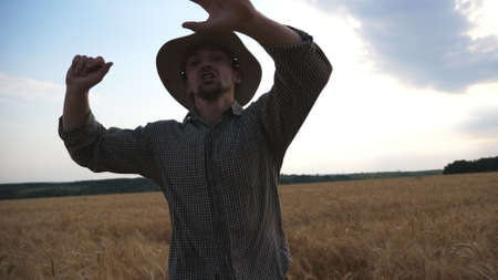 Young annoyed agronomist running to camera through the wheat field and trying to catch somebody. Angry farmer jogging among cereal meadow and tries to kick out someone from plantation. Front viewの写真素材