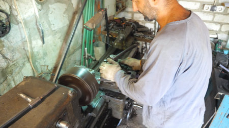 Adult man working with old workbench in his garage or workshop. Mechanic using lathe for metal...