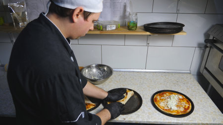 Male chef in gloves wrapping tasty pita bread with cabbage at cuisine. Young cook in uniform...