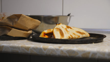 Male hands of chef in gloves putting tasty pita bread with cabbage in a paper bag at kitchen. Arms of cook arranged delicious lavash for being served. Concept of cooking food. Close up Slow motionの写真素材