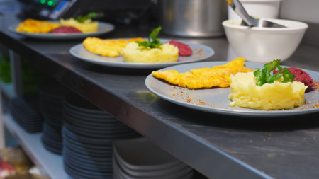 Male hand adding sprigs of parsley onto mashed potatoes on plates. Arm of chef serving puree with crispy breaded chicken fillets at restaurant. Concept of preparing food. Close up Slow motionの写真素材