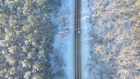 White car riding through snowy rural road. Following to SUV driving at beautiful countryside route...