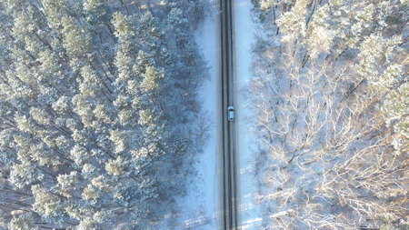 White car riding through snowy rural road. Following to SUV driving at beautiful countryside route on wintry day. Winter holidays journey at nature. Concept of family travel. Aerial shot Top Viewの写真素材