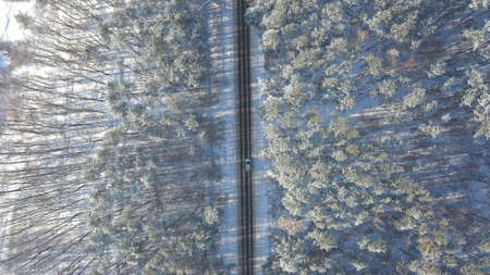 White car riding through snowy rural road. Following to SUV driving at beautiful countryside route on wintry day. Winter holidays journey at nature. Concept of family travel. Aerial shot Top Viewの写真素材