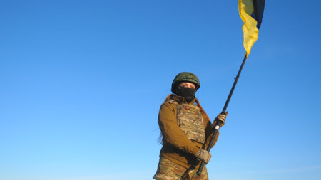Female ukrainian army soldier holding waving flag of Ukraine. Woman in military uniform and helmet...