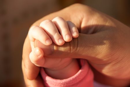 daddy's big tanned palm holds his little daughter's handの写真素材
