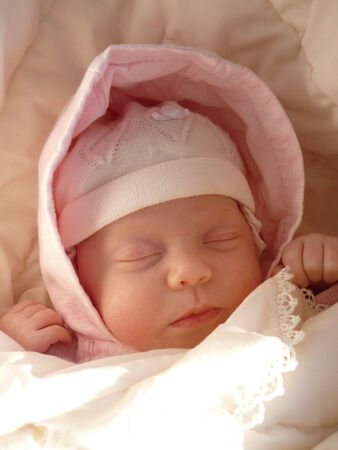 dreaming sweet baby girl in knitted bonnet and pink hood wrapped soft blanket の写真素材
