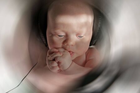 baby girl with thoughtful attention listening to music in big black headphones, space for text on blurred backgroundの写真素材