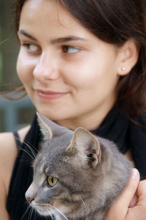 young beautiful dark-haired girl with tabby cat, focus on cat の写真素材