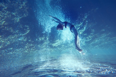 freediving girl with air bubbles and corals, and water surfaceの写真素材