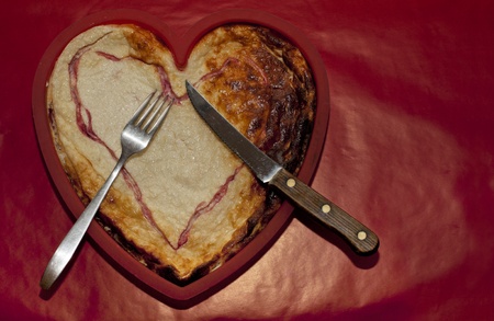 heart-shaped slightly burnt pie served for eater, copy space on red backgroundの写真素材