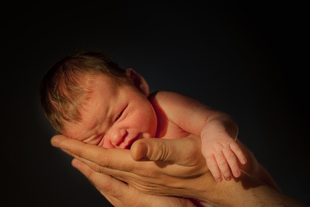 newborn girl 3 days old in father's hands, on black backgroundの写真素材
