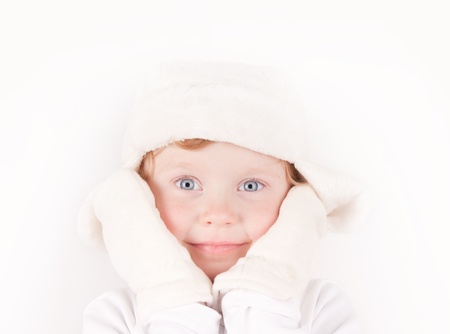little girl in white winter fleece hat with ear flaps & mittens portrait on whiteの写真素材