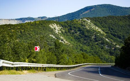 Summer asphalt road in the mountains, leading over the hill. Scenic view of the road in the mountainsの写真素材