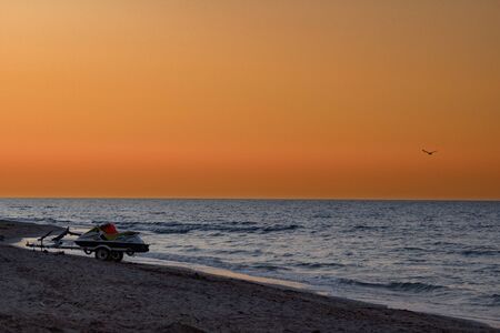 Hydrocycle trailer stands on the shore. Jet ski on the sea coast at sunsetの写真素材