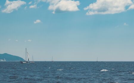 Yachts and small boats sail along the coast, hunt and fish. Boat trips on boats. Clear sky and sunny dayの写真素材