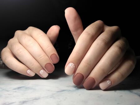 Gentle coffee manicure with white design. Short square nails with brown-beige coating and the design of twigs.の写真素材