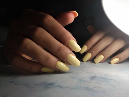 Long square nails with gel polish. Clean manicure with pale yellow coating without design.の写真素材