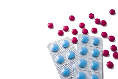 Red and blue pills on white background. Scattered red pills next to blue pills in blistersの写真素材