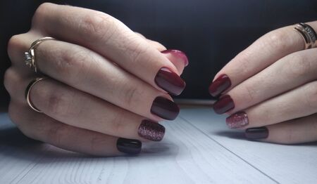 Long square nails with manicure. Gel polish with wine color and brilliant design. Maroon and red coating on the nails.の写真素材