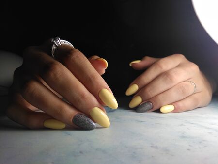 Yellow gel polish with grey design and sequinsの写真素材