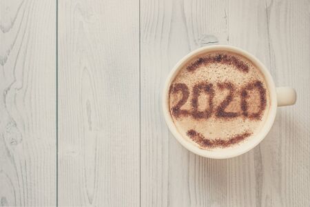 Mug of cappuccino with cinnamon for breakfast.Cinnamon powder is sprinkled with 2020 numbers on...