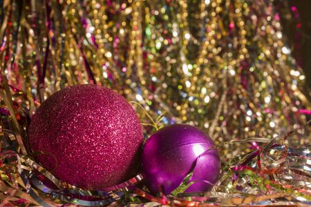 Two red Christmas balls on shiny tinsel. Two Christmas toys of the same color and different sizes. Big shiny red ball and little purple for Christmas treeの写真素材