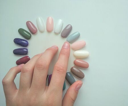 Tips for manicure in the form of chamomile. Palette of pastel colors. The customer chooses the color. Hand shows the color.の写真素材