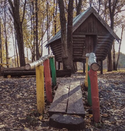 Hut on chicken legs is in the city park. A wooden house made of logs stands on legs. Multicolors handrails on the path to the houseの写真素材