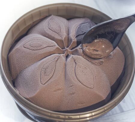 A bucket of chocolate ice cream with a spoon. Spoon took the ice cream with the taste of chocolate....