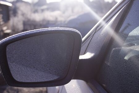 Frozen side mirror of the car. Outer mirror covered with hoarfrost morning winter morning. Hoarfrost from beautiful snowflakes create a pattern on the side mirror of the car.の写真素材