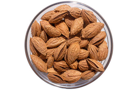 A pile of almonds in a plate on an isolated background. Salted fresh nuts in the shell in a glass...