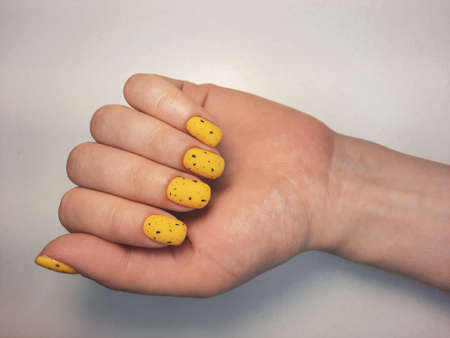Bright yellow gel polish with black splinters. Women's manicure with yellow lacquer and black design. Quail Ðµgg designの写真素材