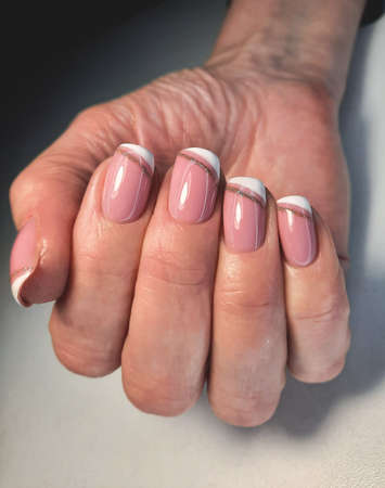 Delicate camouflage gel polish with French design and gold sequins. Women's French manicure.の写真素材