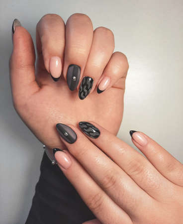 Stylish and strict female manicure with a black French design. Female camouflage manicure with black design and rhinestone.の写真素材